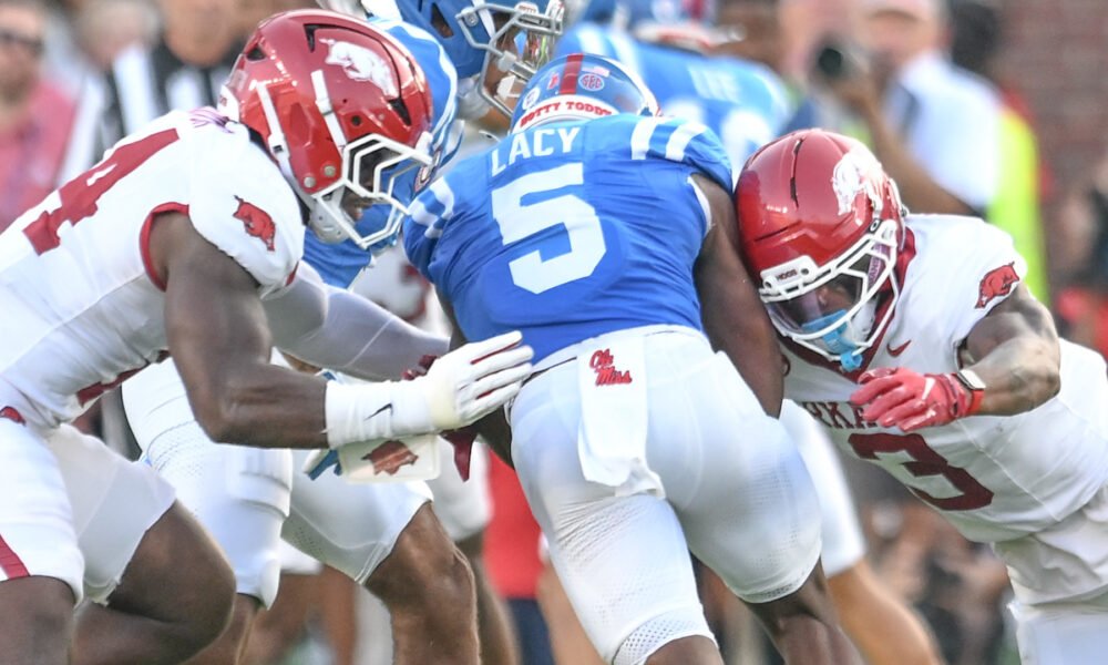 Arkansas Razorbacks defenders Stephen Dix and Larry Worth come together to down Ole Miss Rebels running back Kewan Lacy