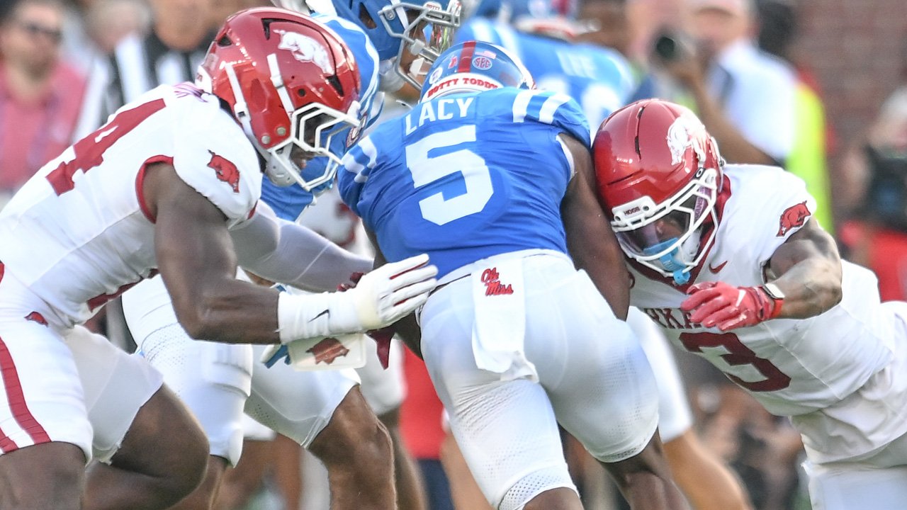 Arkansas Razorbacks defenders Stephen Dix and Larry Worth come together to down Ole Miss Rebels running back Kewan Lacy